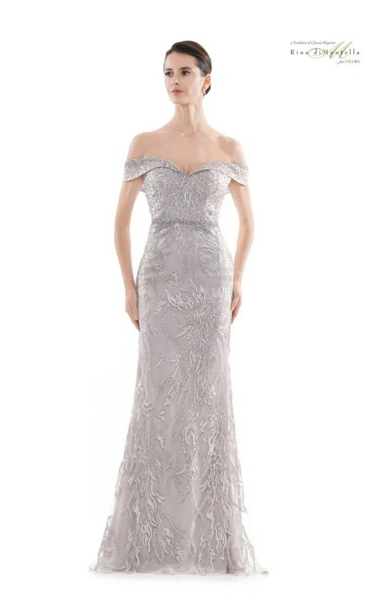 A woman wears the Rina Di Montella RD2713 long formal dress—a light gray, off-the-shoulder, floor-length gown featuring intricate lace and beaded embellishments.
